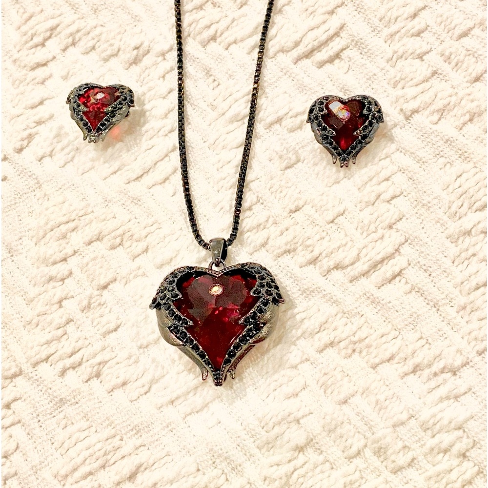 Necklace chain with red heart shaped pendant and earrings.